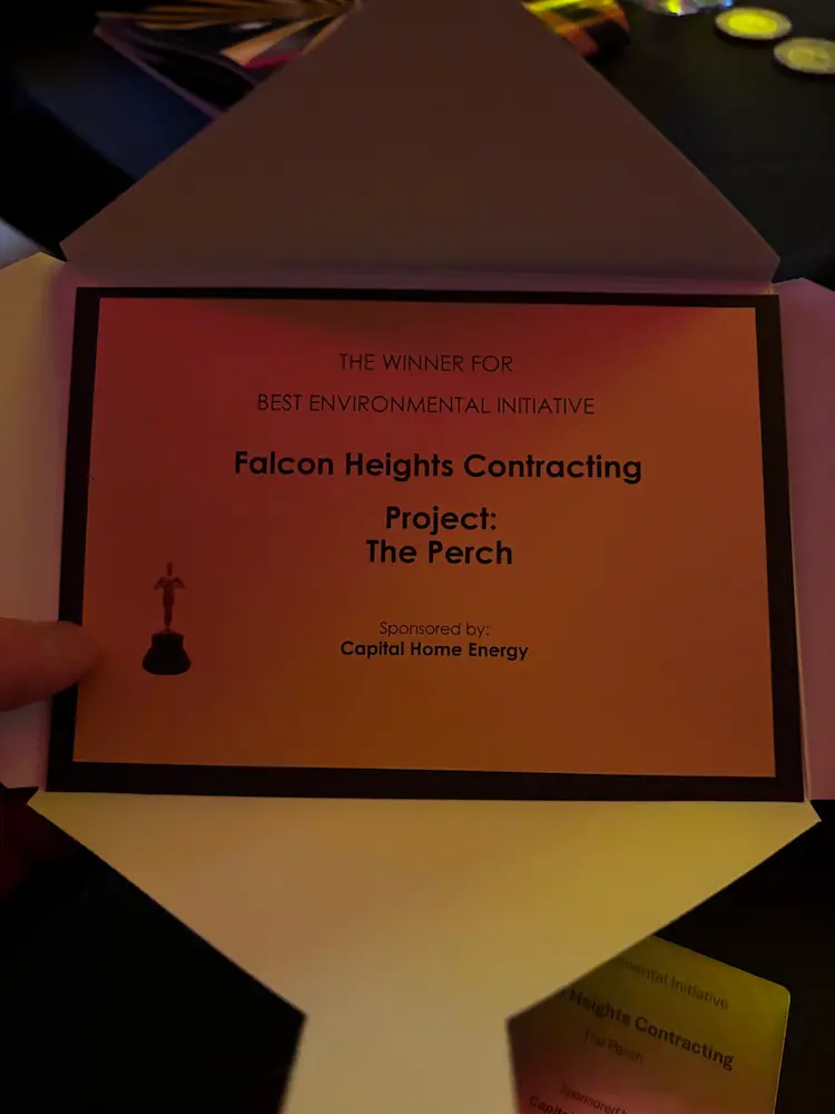 An open envelope displays an award card announcing Falcon Heights Contracting as the 2026 Georgie Awards winner for Best Environmental Initiative for their project The Perch, sponsored by Capital Home Energy.