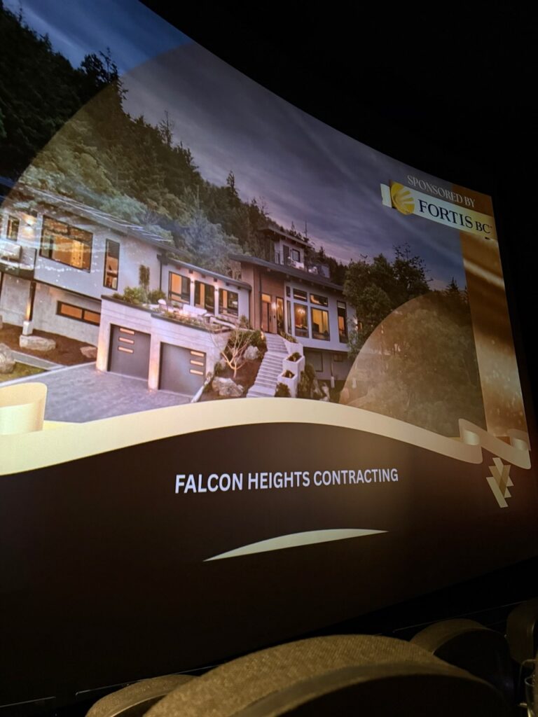 A movie theater screen displays a Falcon Heights Contracting ad featuring a modern home and a Sponsored by Fortis BC logo, highlighting their expertise as a Custom Home Builder. Empty theater seats are visible at the bottom of the image.
